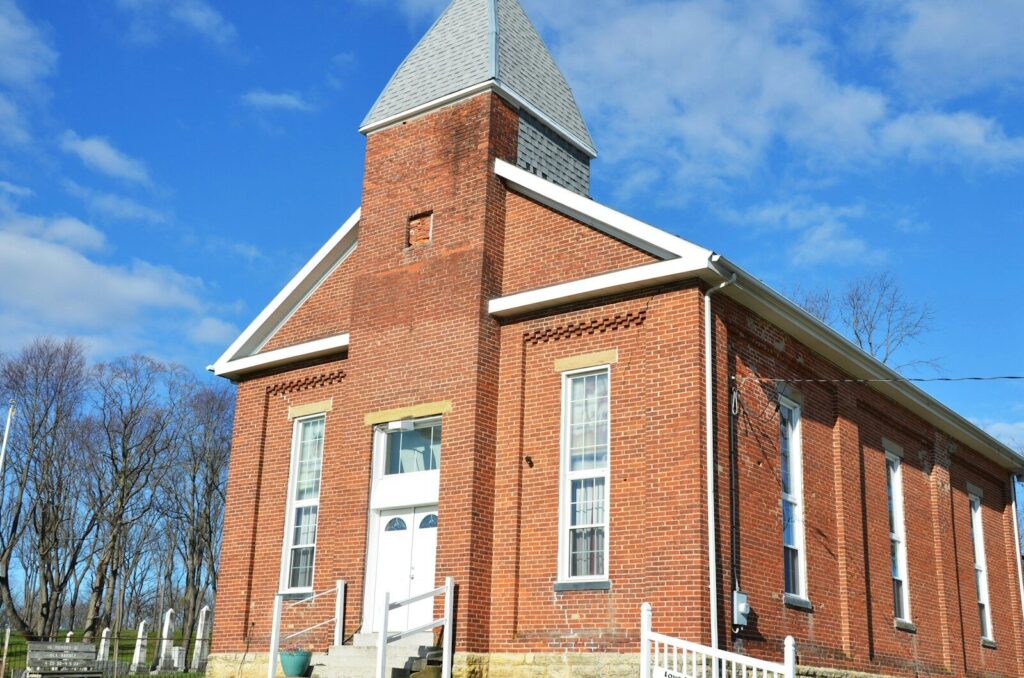 An old brick church with a steeple on a sunny day